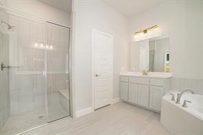 bathroom with a stall shower, tile patterned flooring, a garden tub, and vanity