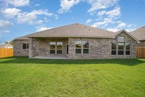 rear view of property featuring a patio area, fence, and a yard