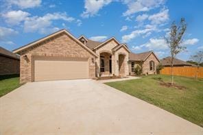 view of front of home featuring driveway, a front lawn, an attached garage, and fence