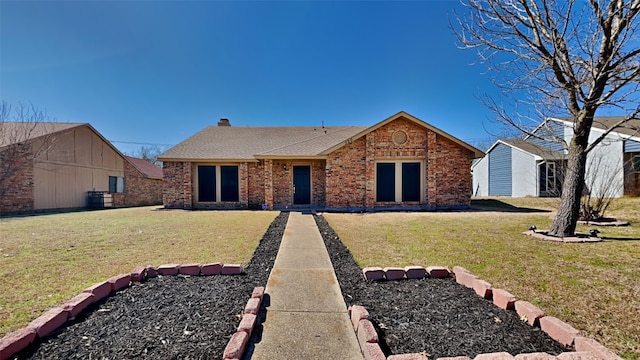 ranch-style house featuring a shingled roof, a front yard, brick siding, and a chimney