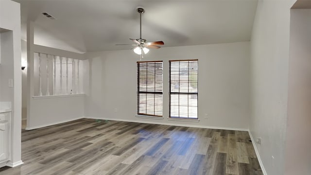 unfurnished room featuring baseboards, visible vents, a ceiling fan, lofted ceiling, and wood finished floors