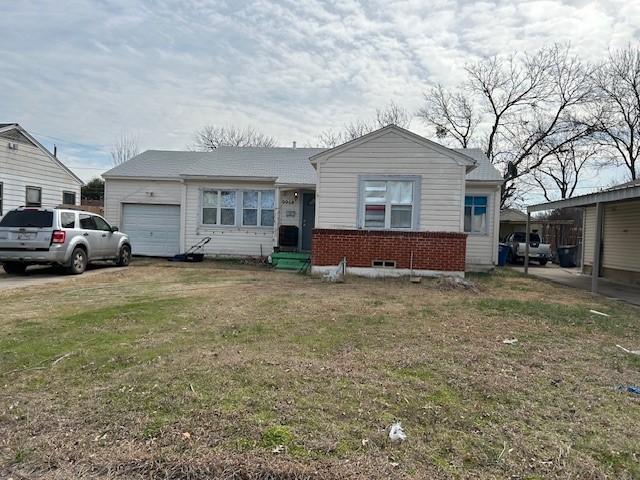 view of front of home with a garage, brick siding, and a front lawn