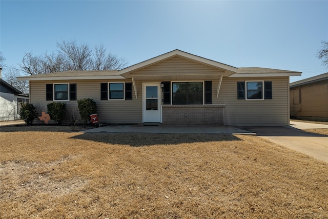 ranch-style house featuring a patio area, brick siding, and a front yard