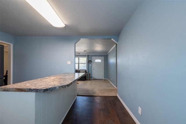 kitchen with baseboards and dark wood-type flooring