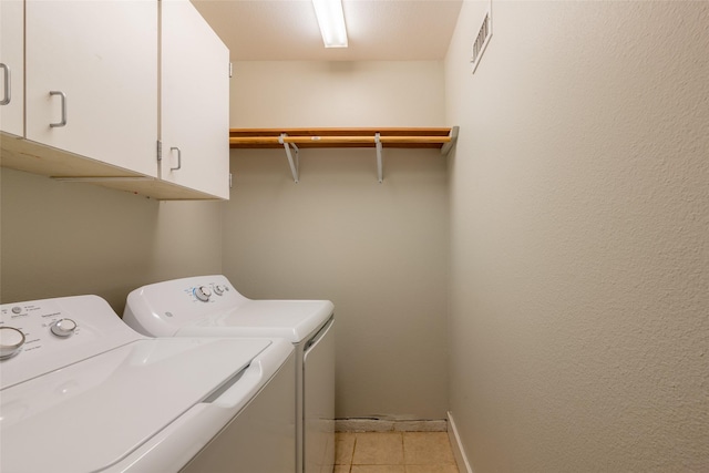 laundry area featuring cabinet space, light tile patterned floors, baseboards, visible vents, and washer and dryer