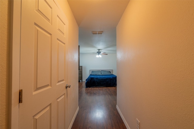 hall with visible vents, dark wood finished floors, and baseboards