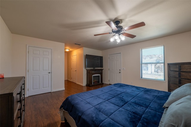 bedroom featuring baseboards, visible vents, a ceiling fan, dark wood-style floors, and a fireplace