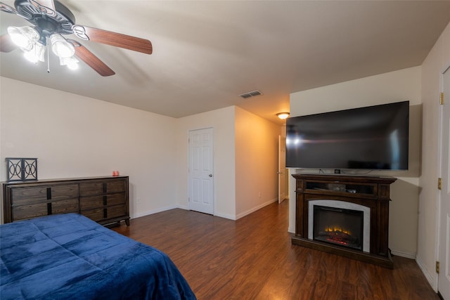 bedroom with a fireplace, wood finished floors, a ceiling fan, visible vents, and baseboards