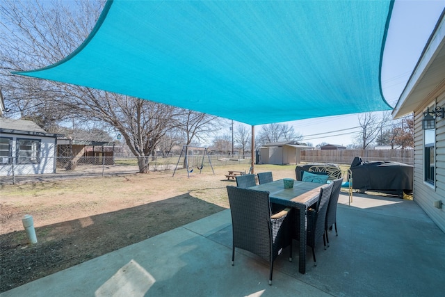 view of patio / terrace with outdoor dining area, a playground, a fenced backyard, a storage shed, and an outdoor structure