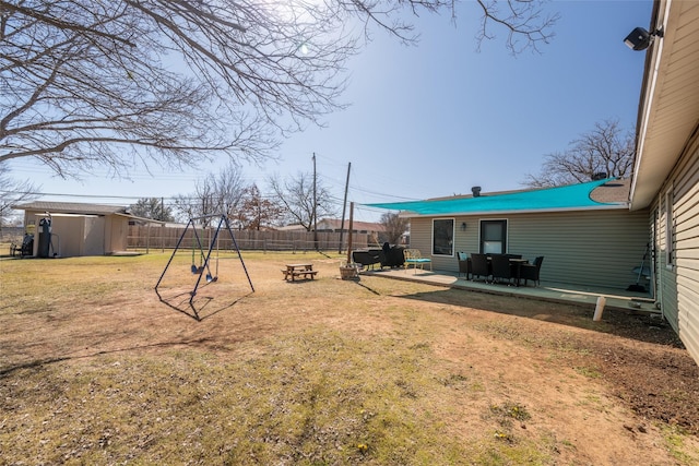 view of yard with a patio, a fenced backyard, a storage unit, an outdoor structure, and a playground