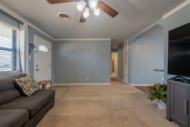 carpeted living area featuring visible vents, crown molding, baseboards, and ceiling fan