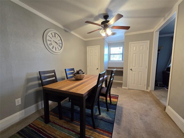 dining room with a ceiling fan, carpet, baseboards, and crown molding