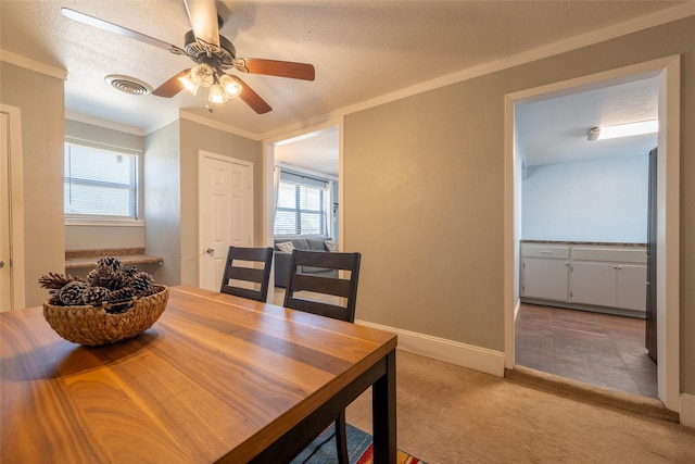 dining space featuring ornamental molding, a ceiling fan, light carpet, a textured ceiling, and baseboards