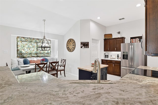 kitchen with stainless steel fridge, visible vents, lofted ceiling, decorative light fixtures, and backsplash