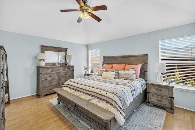 bedroom with vaulted ceiling, multiple windows, light wood-style flooring, and baseboards