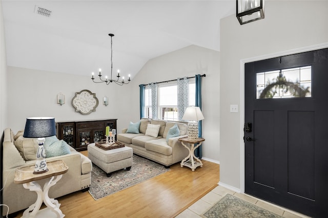 living room with light wood finished floors, visible vents, an inviting chandelier, vaulted ceiling, and baseboards