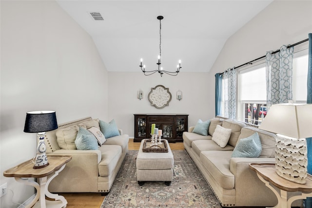 living area with lofted ceiling, wood finished floors, visible vents, and a notable chandelier