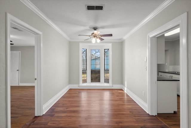 unfurnished room with dark wood-type flooring, visible vents, ornamental molding, and baseboards