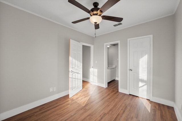 spare room featuring baseboards, visible vents, a ceiling fan, ornamental molding, and wood finished floors