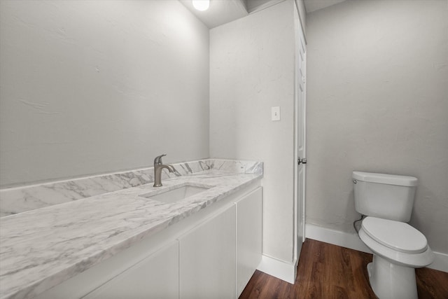 bathroom with baseboards, vanity, toilet, and wood finished floors