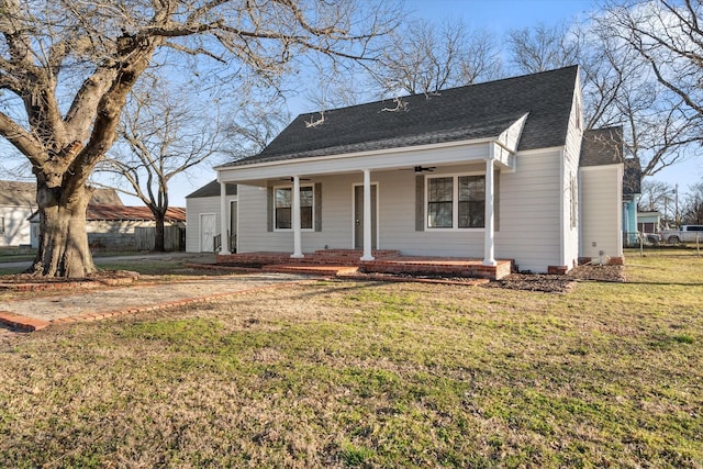 view of front of house featuring a porch, roof with shingles, fence, and a front lawn