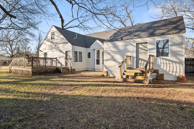 back of property featuring a deck, a yard, and a shingled roof