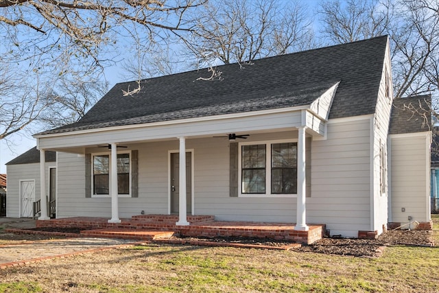 view of front of house featuring covered porch, ceiling fan, a front lawn, and a shingled roof