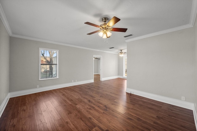 empty room with crown molding, dark wood-style flooring, visible vents, and baseboards