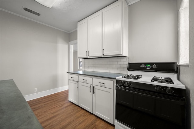 kitchen with dark wood-style floors, visible vents, white cabinetry, and gas range