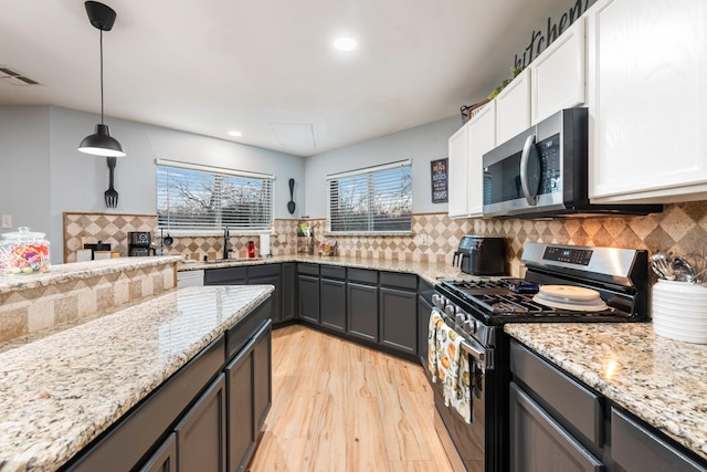 kitchen featuring stainless steel appliances, light wood-style floors, a sink, and light stone countertops