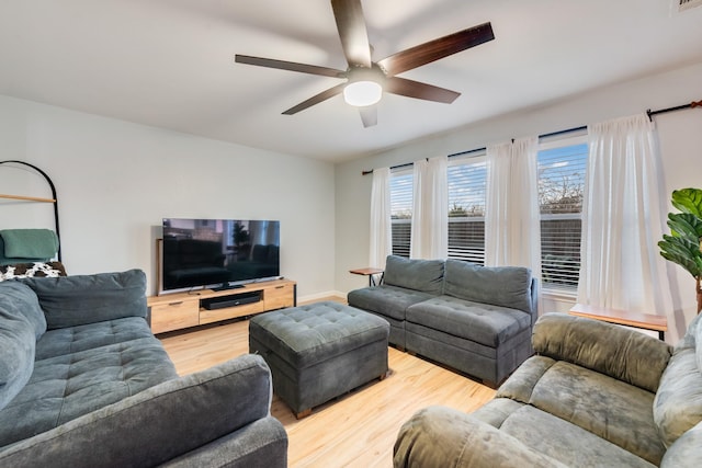 living room with ceiling fan, baseboards, and wood finished floors