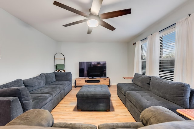 living room featuring light wood-type flooring, ceiling fan, and baseboards