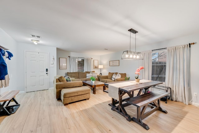 living room featuring light wood-type flooring, baseboards, and visible vents