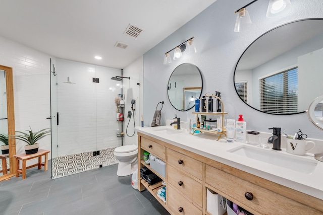 bathroom featuring toilet, a stall shower, a sink, and visible vents