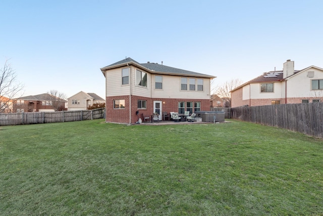 back of property with a yard, brick siding, a patio area, and a fenced backyard