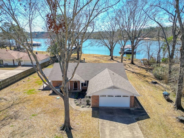 view of front of home featuring brick siding, a shingled roof, concrete driveway, a water view, and a garage