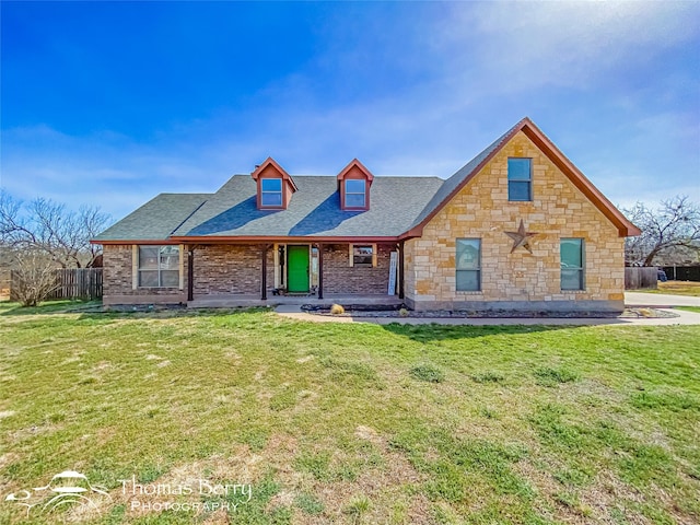 view of front of home with a shingled roof, a front yard, and fence