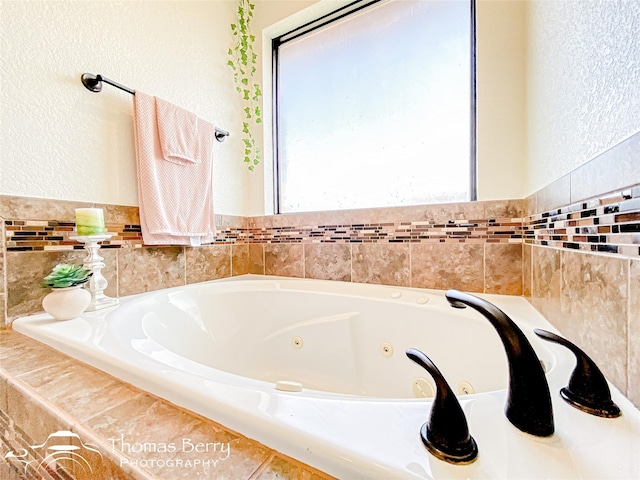 full bathroom featuring a textured wall and a jetted tub