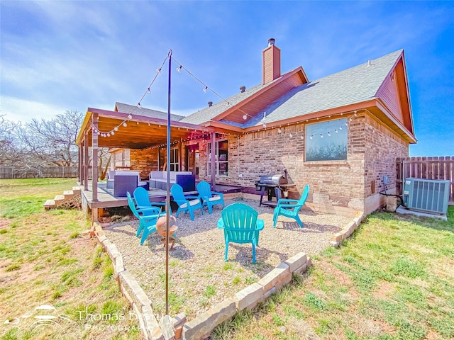 rear view of property with central AC unit, a lawn, a chimney, fence, and brick siding