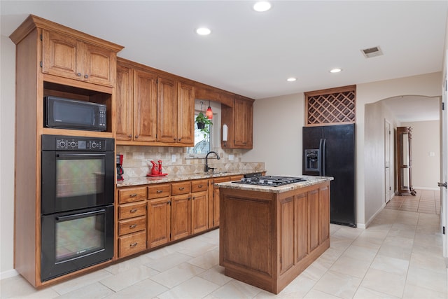 kitchen featuring arched walkways, visible vents, decorative backsplash, light stone countertops, and black appliances