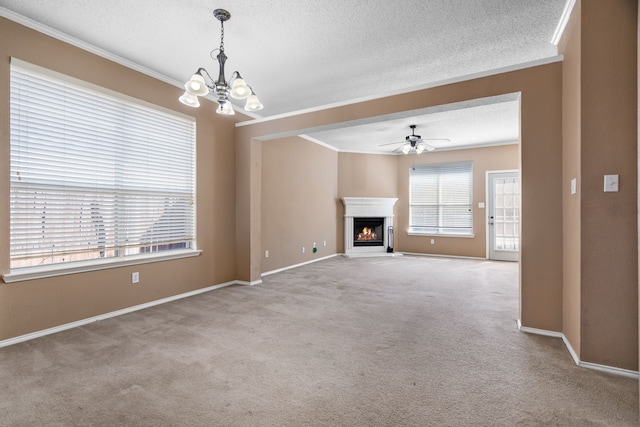 unfurnished living room with a warm lit fireplace, carpet floors, a textured ceiling, and crown molding