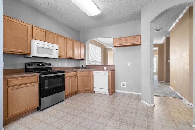 kitchen with white appliances, visible vents, arched walkways, and a sink