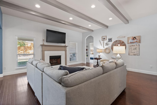 living room featuring dark wood-type flooring, beam ceiling, and baseboards