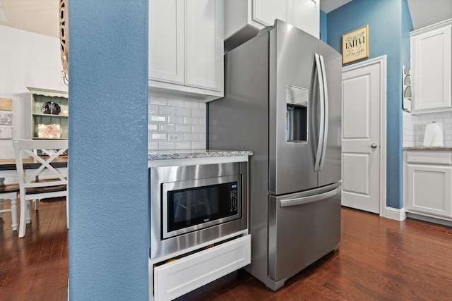 kitchen featuring white cabinetry, appliances with stainless steel finishes, backsplash, light stone countertops, and dark wood finished floors