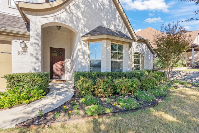 property entrance featuring brick siding and roof with shingles