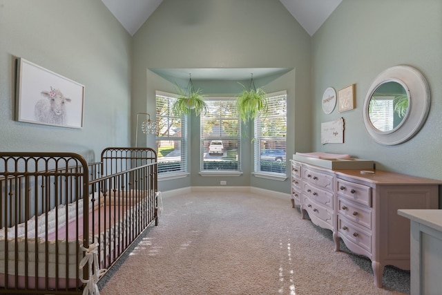 bedroom with high vaulted ceiling, a nursery area, light carpet, and baseboards