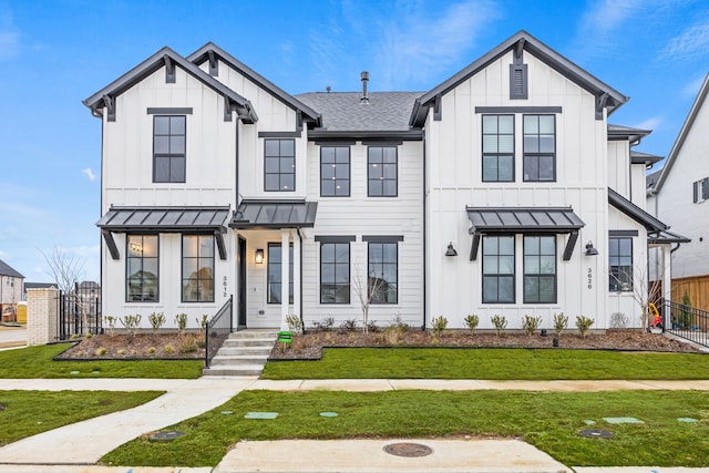 modern farmhouse style home featuring a shingled roof, a standing seam roof, fence, a front lawn, and board and batten siding