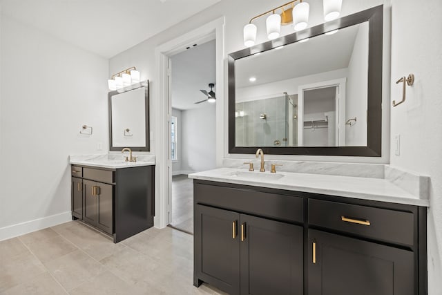 full bath with baseboards, a ceiling fan, a sink, a shower stall, and two vanities