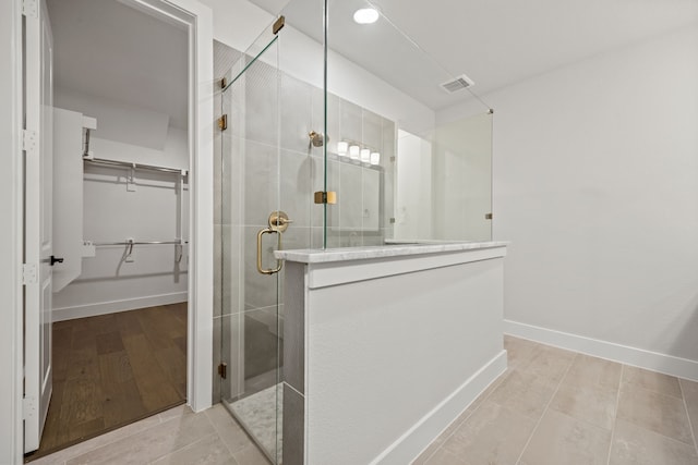 bathroom with visible vents, baseboards, tile patterned flooring, a spacious closet, and a shower stall