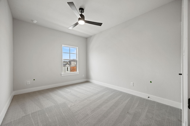 carpeted empty room featuring ceiling fan and baseboards